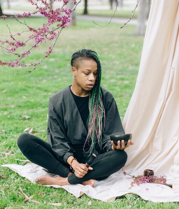 Smiling woman sitting in a lotus yoga pose outdoors.